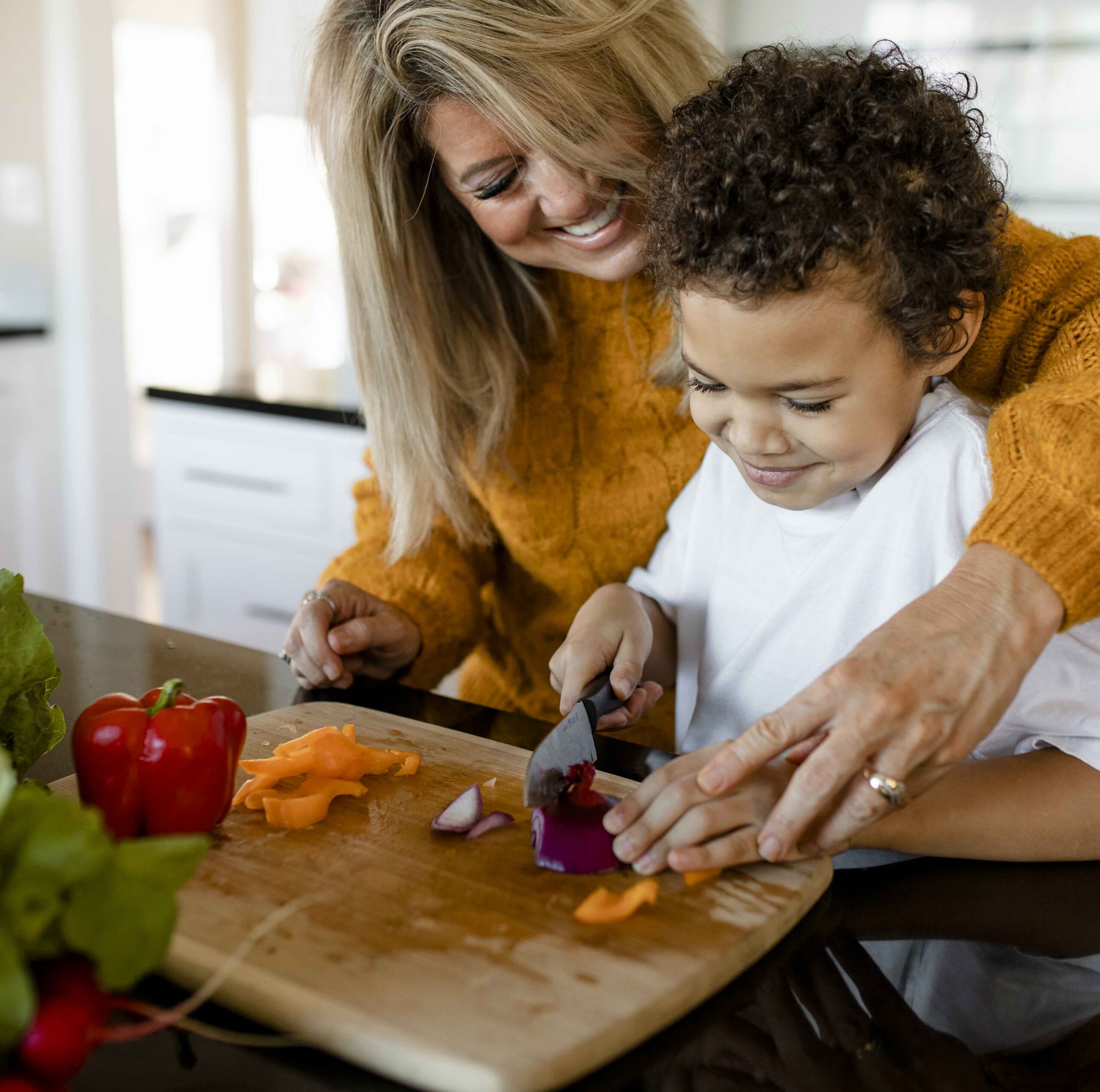Family cooking breakfast together at home Mother and son chopping vegetables together in the kitchen.