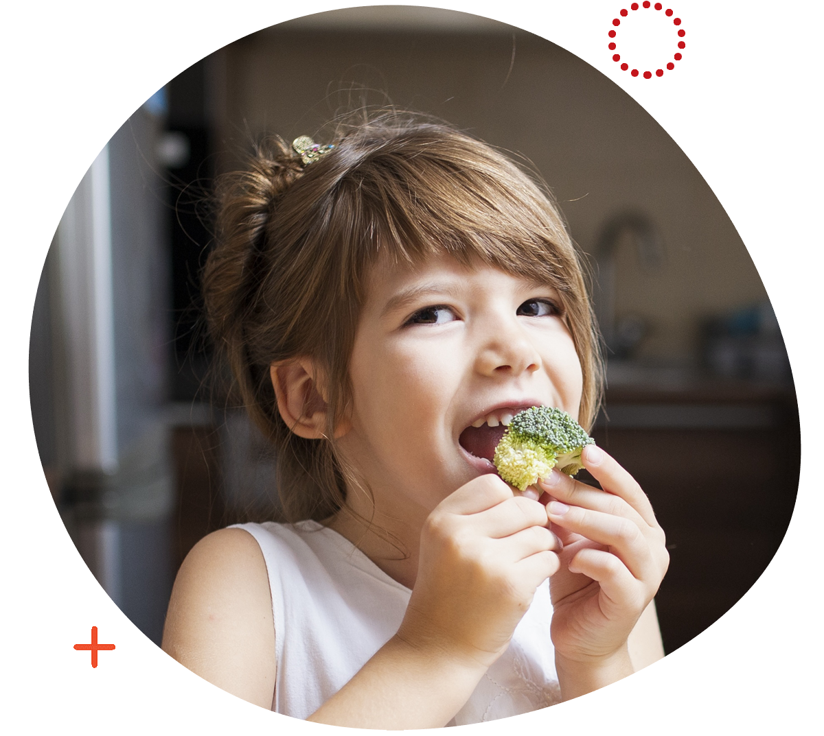 Image by Freepik. Young girl smiling and eating a bite of broccoli.