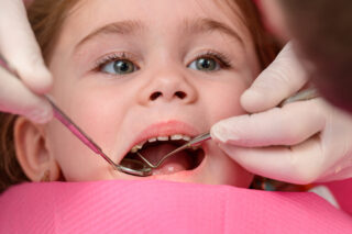 Dentist examining young girl's baby teeth.